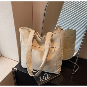 Detailed shot of beige large capacity tote bag with front zipper pocket and long strap