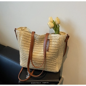 Détail d'un sac cabas en paille tressée avec lanières en cuir marron et boucle en métal