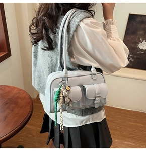 Dettaglio della borsa Boston azzurra in vernice con ciondolo a orso e tasche laterali