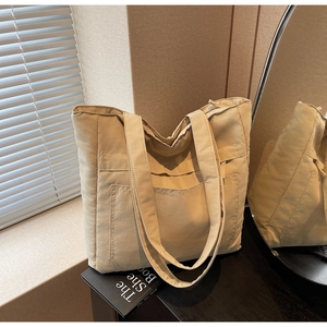 Detail of a large beige nylon tote bag with a front pocket in natural soft light