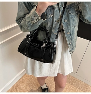 Detail of glossy black dumpling bag showing shiny leather texture and silver buckle accents