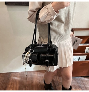 Dettaglio della borsa Boston nera lucida con tasche con fibbia e ciondolo a forma di orsetto