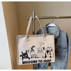 Nahaufnahme der beigen Stofftasche mit schwarz-weißen Comic-Prints am Kleiderbügel