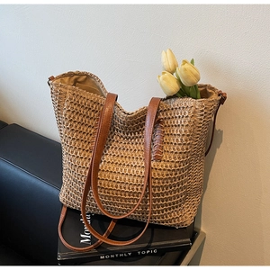 Détail d'un sac cabas en paille tissée avec anses en cuir marron et texture naturelle