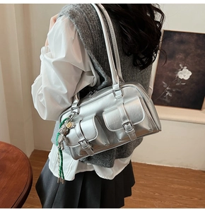 Dettaglio della borsa Boston argento Y2K con multitasche e accessorio con ciondolo a orsetto