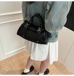 Detail of black patent leather dumpling bag with silver buckles and gloss finish