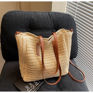 Détail du sac cabas en paille tissée beige avec anses en cuir marron et finitions