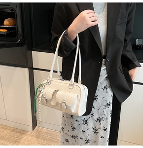 Dettaglio della borsa Boston in pelle bianca con tasche frontali e ciondolo in seta
