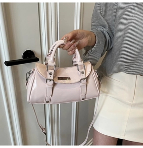 Detail of pale pink patent leather bag with mirror finish and metal hardware