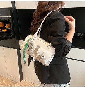 Dettaglio della borsa a spalla crema in pelle PU con tasche utility e ciondolo orso