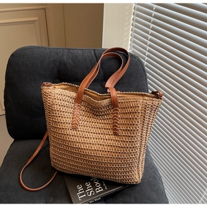 Gros plan sur la texture tressée et la bandoulière en cuir brun du sac cabas en paille