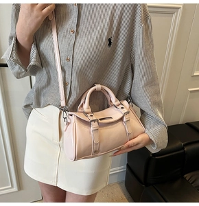 Detail of pink faux leather satchel bag with metallic buckle straps and glossy finish