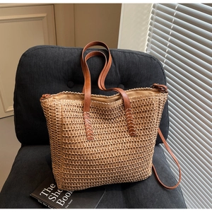 Détail du cabas en paille tissée avec anses en cuir marron et coutures en croix