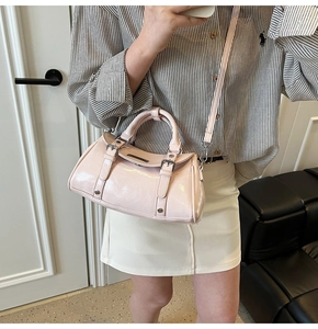 Close-up of pink glossy Boston bag with buckle straps and metallic stud details