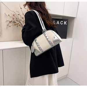 Detail of cream and silver bowling bag with metal studs and chain strap on shoulder