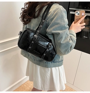 Detail of black crinkled leather Boston bag with metallic buckles and punk style