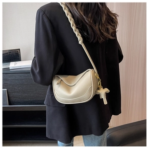 Detail of beige lychee texture dumpling bag featuring woven strap and elephant charm