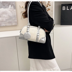 Detail of silver chain and metallic rivet accents on an off-white shoulder bag
