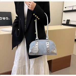 Detail of blue leather bowling bag with silver metallic accents and brand charm