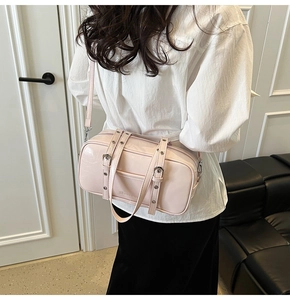 Detailed side view of light pink shiny leather crossbody bag with silver eyelet straps