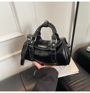 Detail of black glossy patent leather handbag with silver hardware and adjustable strap
