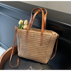 Détail du sac cabas en paille montrant les coutures des poignées en cuir et la doublure