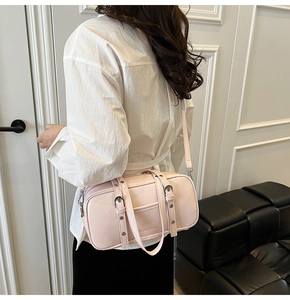 Side view of a light pink patent leather Boston bag styled as a shoulder bag on a model