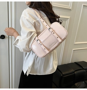 Side view of pink glossy patent leather Boston bag with metal buckle shoulder straps