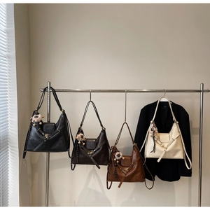 Detail display of four tote bags in black brown and cream with plush ball charms