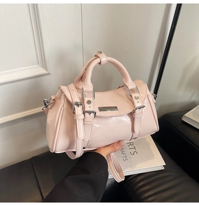 Close-up of light pink patent leather handbag with silver hardware and adjustable strap