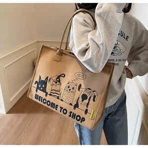 Seitenansicht einer khakifarbenen Canvas-Tasche mit Cartoon-Illustrationen getragen von Model