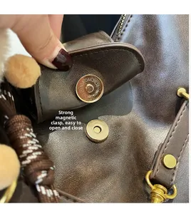 Detailed close-up of strong magnetic buckle on dark brown leather tote bag