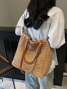 Grand sac cabas d'été en paille avec bandoulières en cuir marron porté à l'épaule