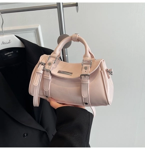 Detail of light pink patent leather handbag with dual buckles and silver metal accents