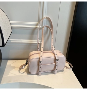 Detail of pink faux leather Boston bag featuring decorative metal eyelets on straps