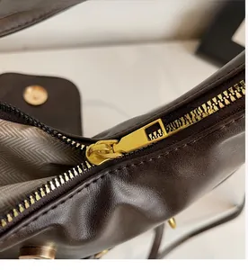 Detail of smooth gold zipper and herringbone lining on brown faux leather tote bag