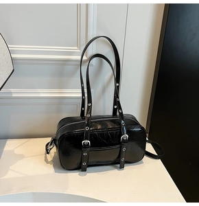 Close-up of black glossy pillow bag with silver eyelets and engraved bottom detail