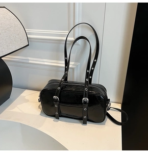 Detail of black glossy Boston bag with eyelet straps and decorative vertical buckles