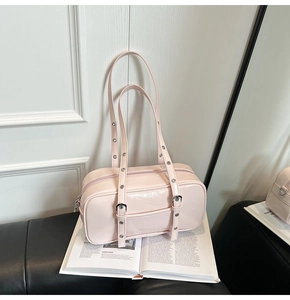 Detail of pink faux leather Boston bag with metallic eyelet straps on book background