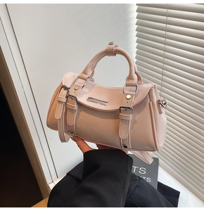 Detail of pink faux leather dumpling bag with metal buckle straps and round handle