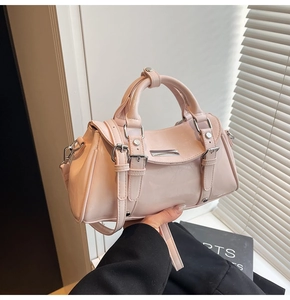 Detail of glossy pale pink dumpling bag with silver hardware and smooth patent leather finish
