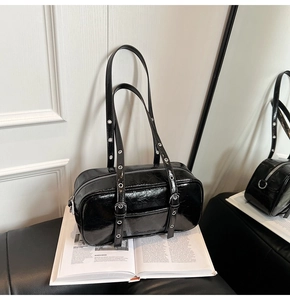 Detail of black glossy wrinkled shoulder bag with metallic eyelets on the strap