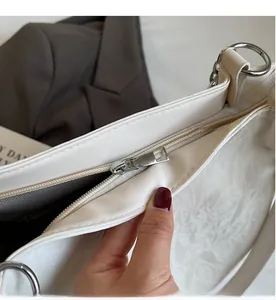 Detailed close-up of smooth silver zipper and textured cream leather on tote bag