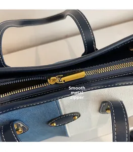 Close-up of golden metal zipper puller on blue denim and white canvas tote bag