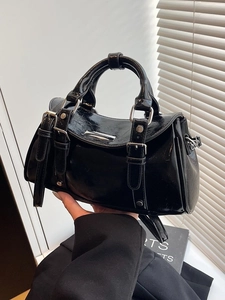 Glossy black dumpling bag with silver hardware in a minimalist urban handbag style