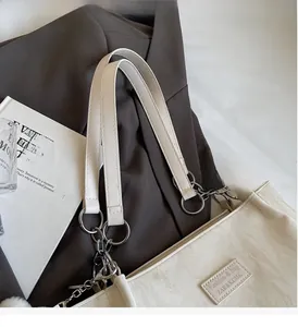Detail of white marble-textured tote bag showing the metal ring and leather brand tag
