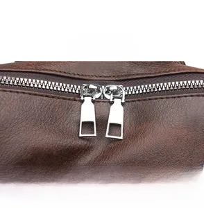 Detail view of durable silver dual metal zippers on brown lychee pattern leather backpack