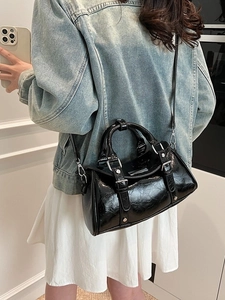 Glossy black pleated dumplings bag with silver rings shown as a crossbody handbag
