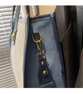 Detail of premium golden metal buckles and canvas texture on a stylish patchwork tote bag