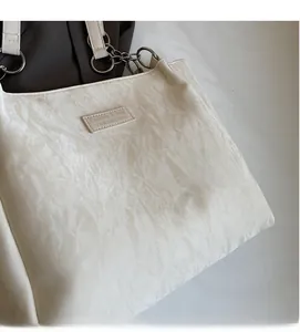 Detailed view of cream pleated fabric texture and fashion label on shoulder tote bag